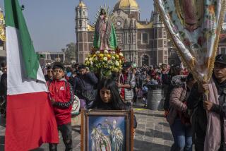 A group of people carry a clay figure of the Virgin walk out from the Basilica of Guadalupe
