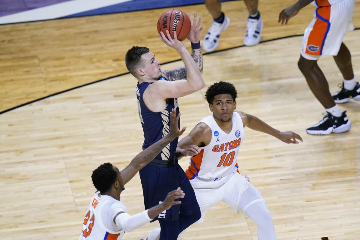 Oral Roberts guard Carlos Jurgens, center, shoots over Florida guard Scottie Lewis and guard Noah Locke.