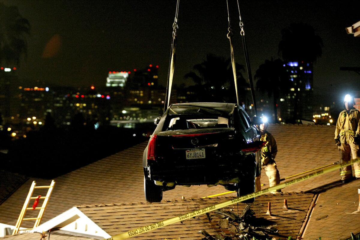 A car is removed by crane from the roof of a home on the 400 block of Audraine Dr. in Glendale on Saturday, March 23, 2013. The driver told police he lost his brakes. The car went onto a neighbor's lawn and launched off onto the roof of the lower house down the street.