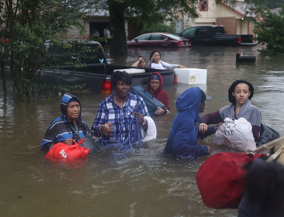 People evacuate their flooded homes on Monday in Houston.