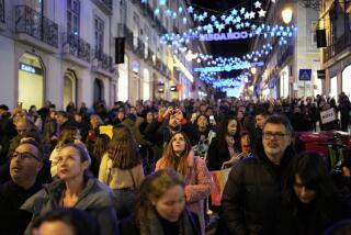 People look up at Christmas lights as crowds stroll around downtown Lisbon's Chiado neighborhood, Saturday evening, Dec. 23, 2023. (AP Photo/Armando Franca)