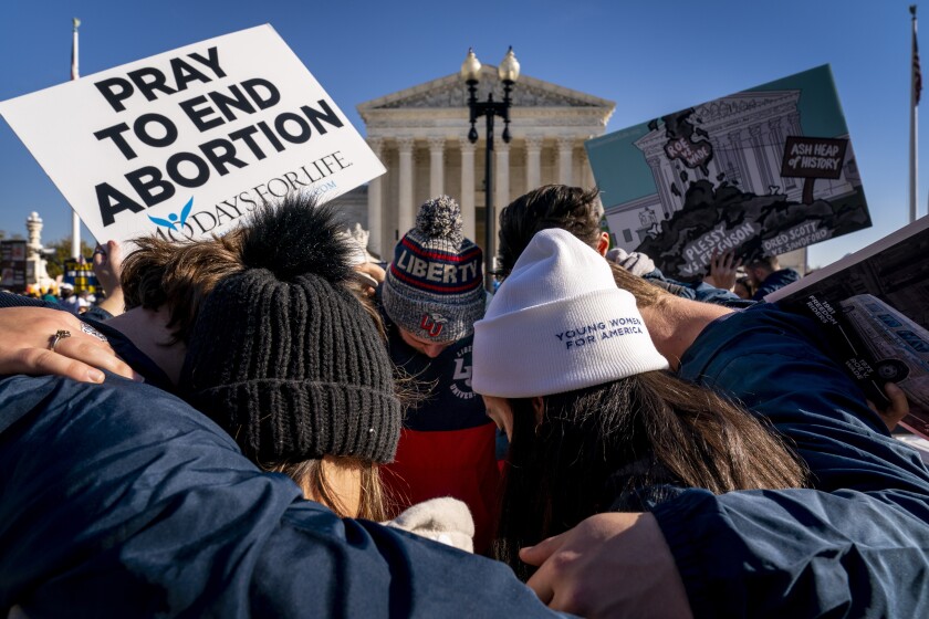 A group of anti-abortion protesters pray together in front of the U.S. Supreme Court, Dec. 1, 2021.