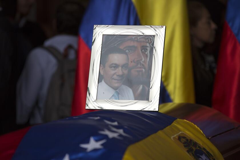 FILE - A framed portrait of opposition activist Fernando Alban shadowed by an image of Jesus Christ sits on the flag-draped casket containing his remains, during a solemn ceremony at the National Assembly headquarters, in Caracas, Venezuela, Tuesday, Oct. 9, 2018. A federal judge in Miami has awarded on September 2022, $73 million in damages to Alban´s family who died while in custody in what he described as a “murder for hire” carried out by a criminal enterprise led by President Nicolas Maduro. (AP Photo/Ariana Cubillos, File)