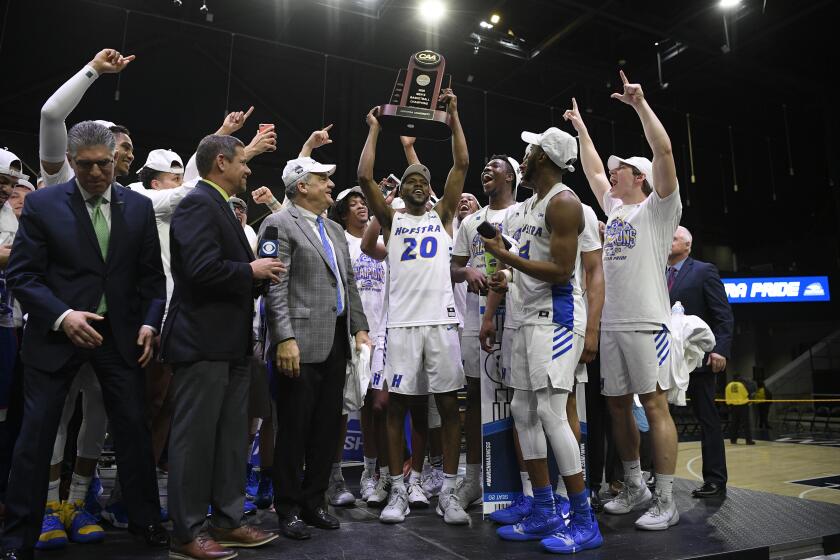 Hofstra guard Jalen Ray (20) and others raise the trophy after defeating Northeastern in an NCAA college basketball game for the championship of the Colonial Athletic Association men's tournament Tuesday, March 10, 2020, in Washington. Hofstra won 70-61. (AP Photo/Nick Wass)