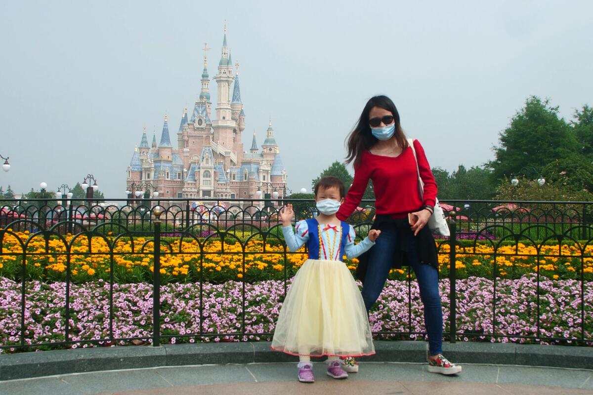 Visitors wearing face masks visit the recently reopened Shanghai Disneyland. 