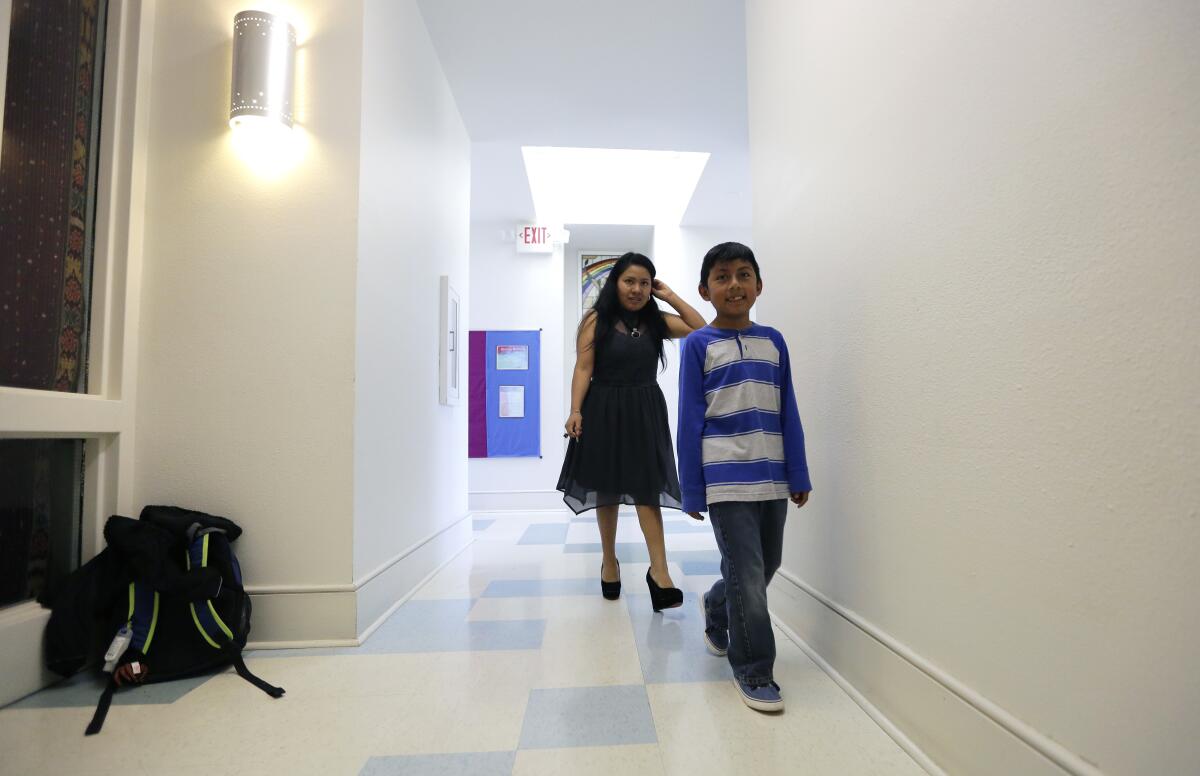 Hilda Ramirez and her son, Ivan, walk past the their living area at St. Andrew's Presbyterian Church.
