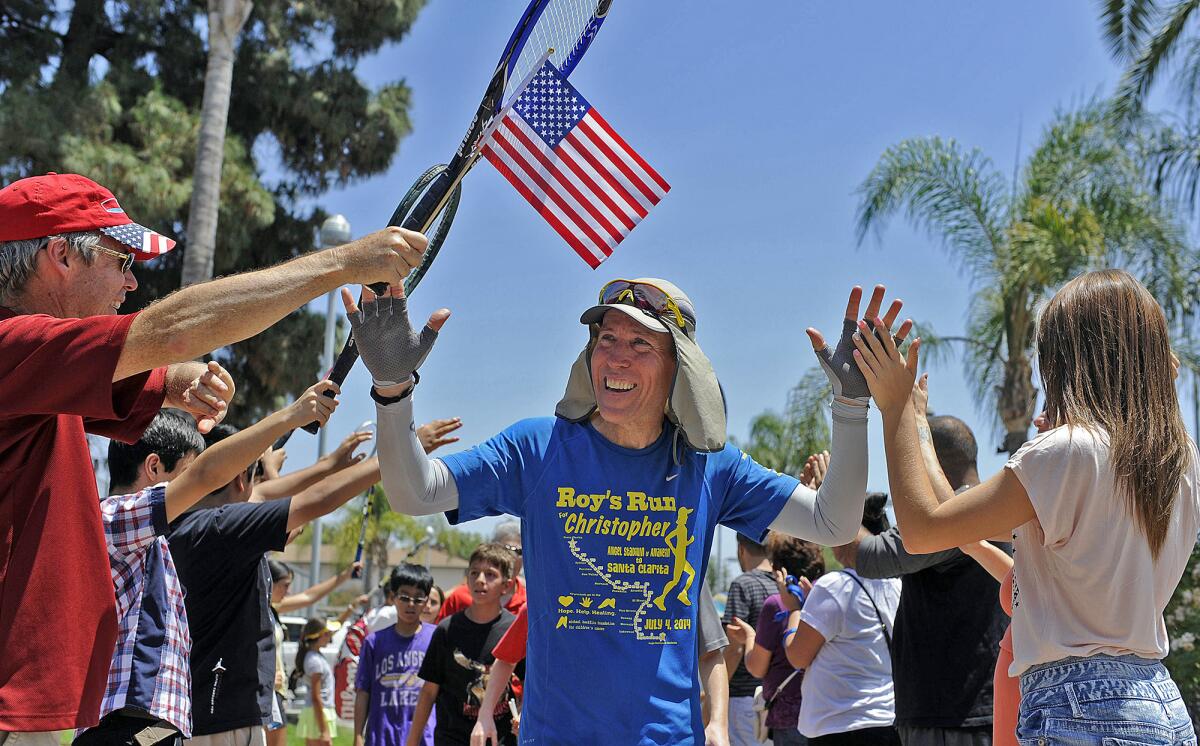 Burbank resident Roy Wiegand high-fives people in rows flanking him outdoors.