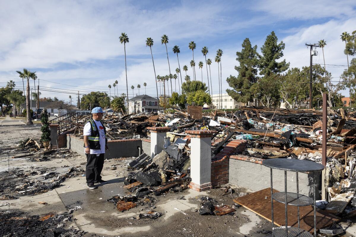 A person looks at the remains of a burned building.