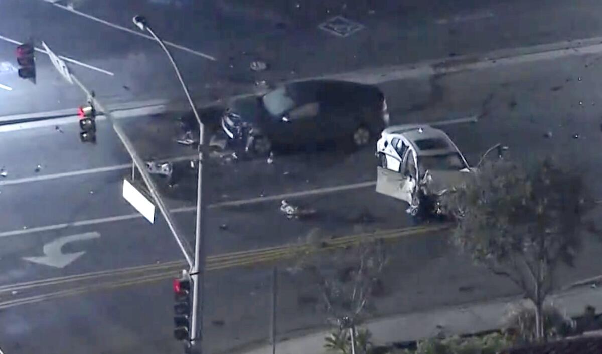 Two damaged cars in the street are surrounded by debris.