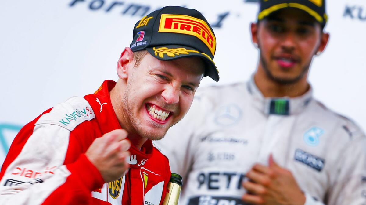 Ferrari driver Sebastian Vettel celebrates on the podium in front of runner-up Lewis Hamilton after winning the Formula One Malaysian Grand Prix on Sunday.