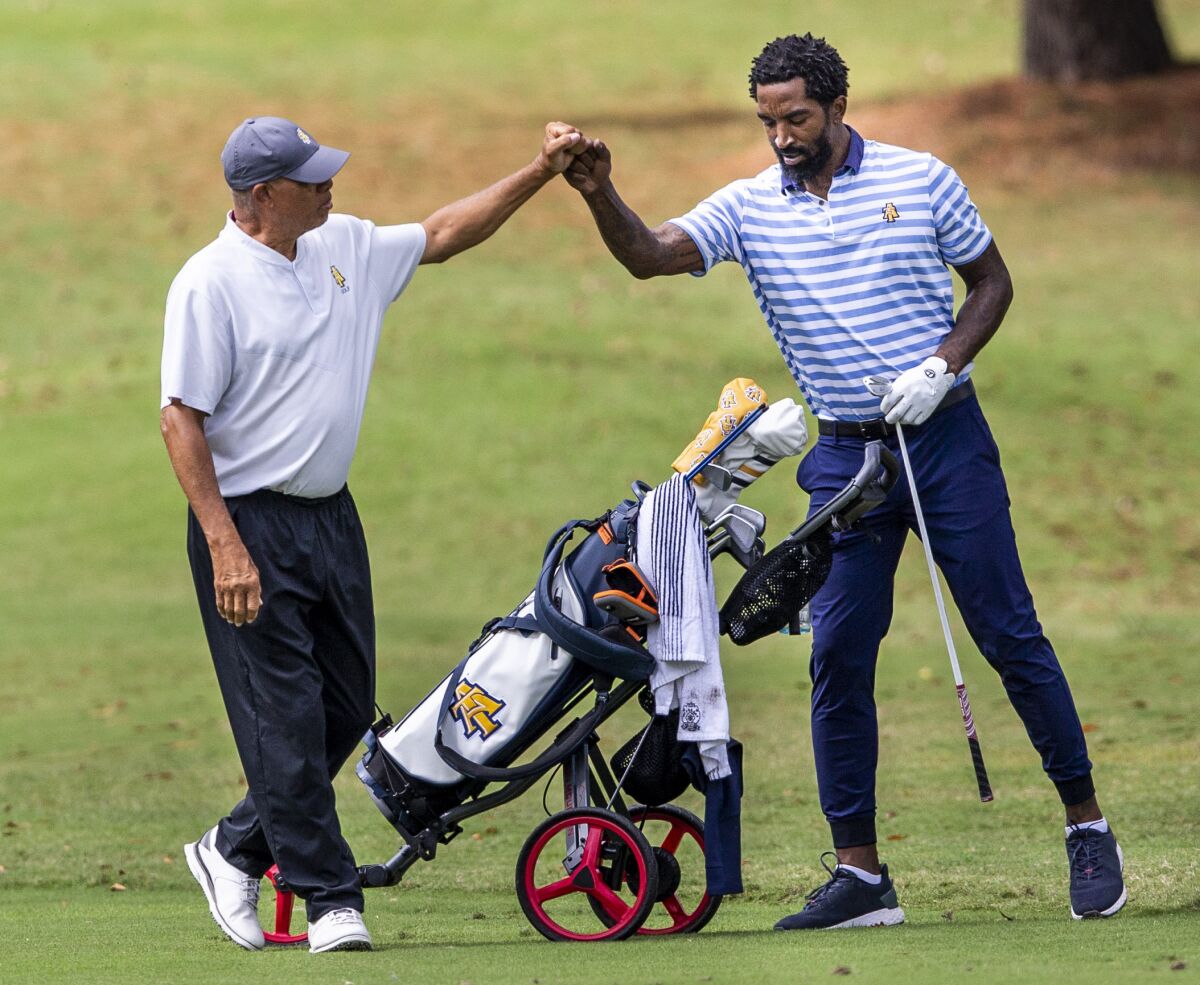 North Carolina A&T head golf coach Richard Watkins, left, bumps fists with and North Carolina A&T's J.R. Smith on the ninth hole during the second round of the Phoenix Invitational golf tournament in Burlington, N.C., Tuesday, Oct. 12, 2021. Smith spent 16 years playing in the NBA, winning two world championships. (Woody Marshall/News & Record via AP)