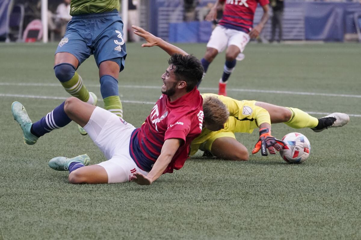 FC Dallas forward Ricardo Pepi, left, lands after jumping over Seattle Sounders goalkeeper Stefan Cleveland during the first half of an MLS soccer match Wednesday, Aug. 4, 2021, in Seattle. (AP Photo/Ted S. Warren)