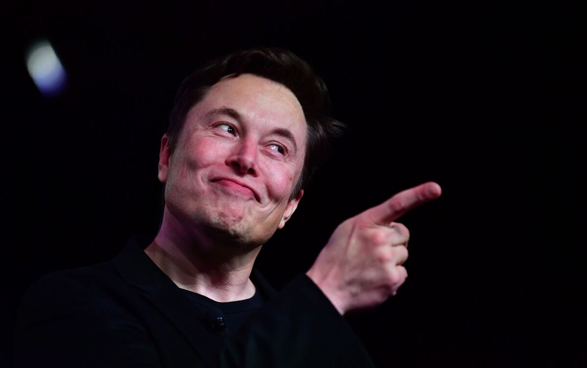 Tesla CEO Elon Musk points his finger and smiles.