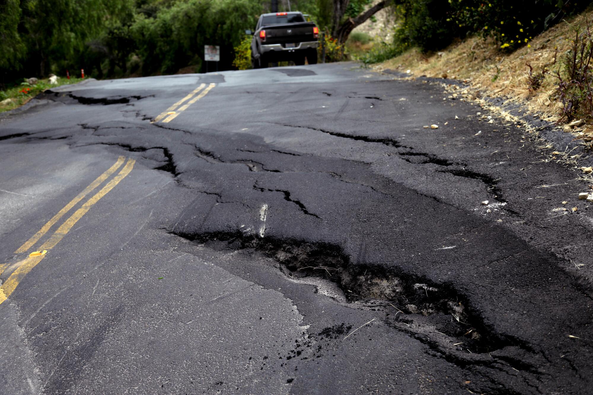 A road whose buckled pavement has been patched.