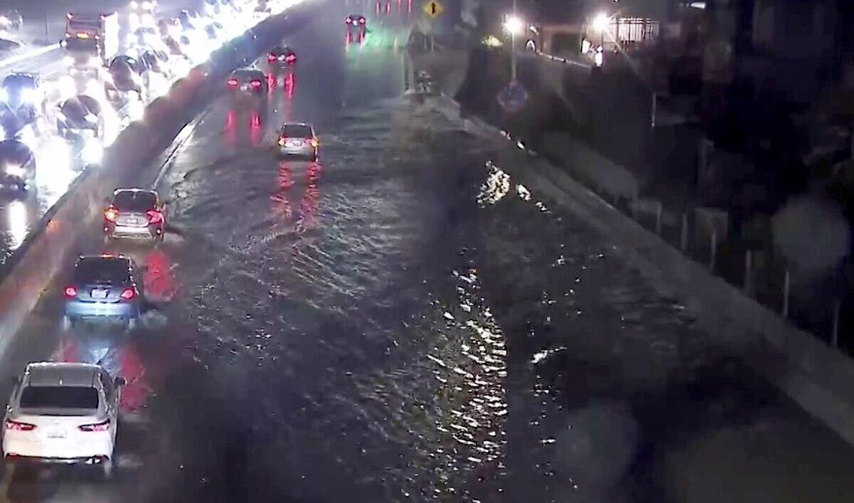 Cars make their way along a flooded freeway illuminated by vehicle headlights 