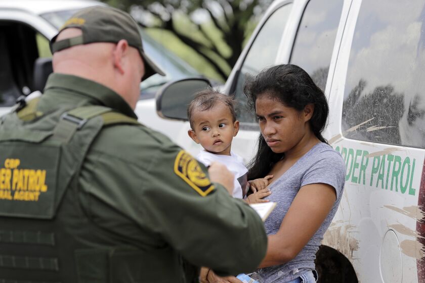 ARCHIVO - Una mujer proveniente de Honduras sostiene a su hijo de 1 año mientras se entrega a un agente de la Patrulla Fronteriza tras cruzar ilegalmente la frontera de Estados Unidos con México, el lunes 25 de junio de 2018, cerca de McAllen, Texas. (AP Foto/David J. Phillip, archivo)