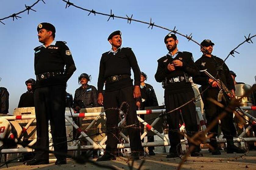 Pakistani riot police and barbed wire form a line to stop a small group of protesters from marching toward government buildings in Islamabad, the nation's capital.