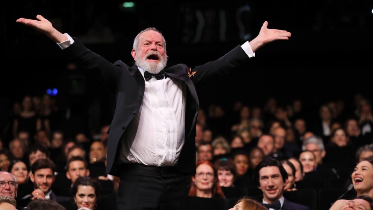 Terry Gilliam stands on his chair to acknowledge applause at the premiere of his film at Cannes this year.