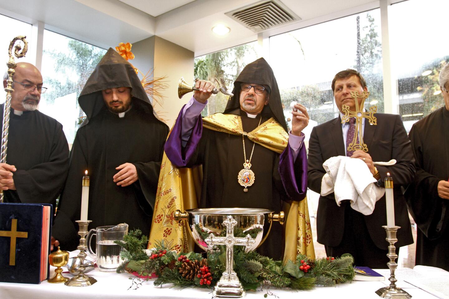 H.E. Archbishop Moushegh Mardirossian, Prelate, center, pours holy oil onto blessed water during Armenian Christmas Service at Dignity Health Glendale Memorial Hospital and Health Center in Glendale on Tuesday, January 5, 2016. Glendale mayor Ara Najarian, right, was pronounced the Godfather of the ceremony.