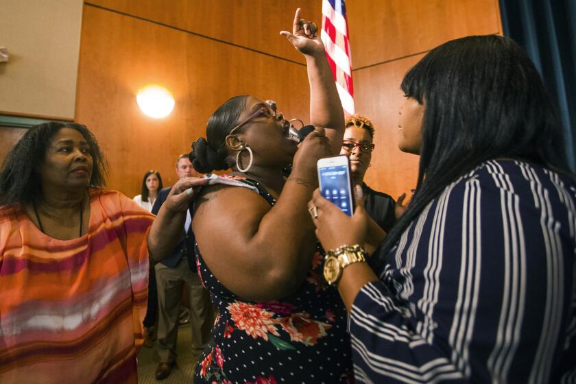 Komaneach Wheeler is restrained by family as she yells at Democratic presidential candidate and South Bend Mayor Pete Buttigieg during a town hall community meeting, Sunday, June 23, 2019, at Washington High School in South Bend, Ind. Buttigieg faced criticism from angry black residents at the emotional town hall meeting, a week after a white police officer fatally shot a black man in the city. (Robert Franklin/South Bend Tribune via AP)