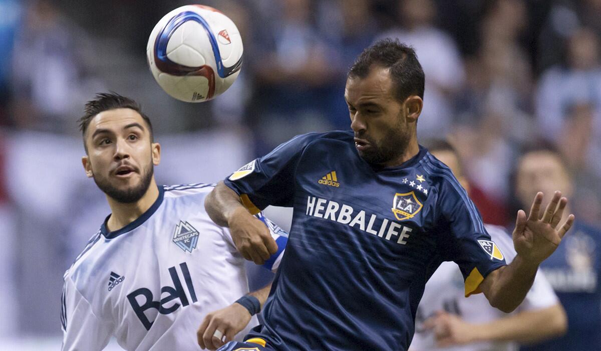 Galaxy's Juninho and Whitecaps' Pedro Morales vie for the ball during the first half of the game on Saturday.