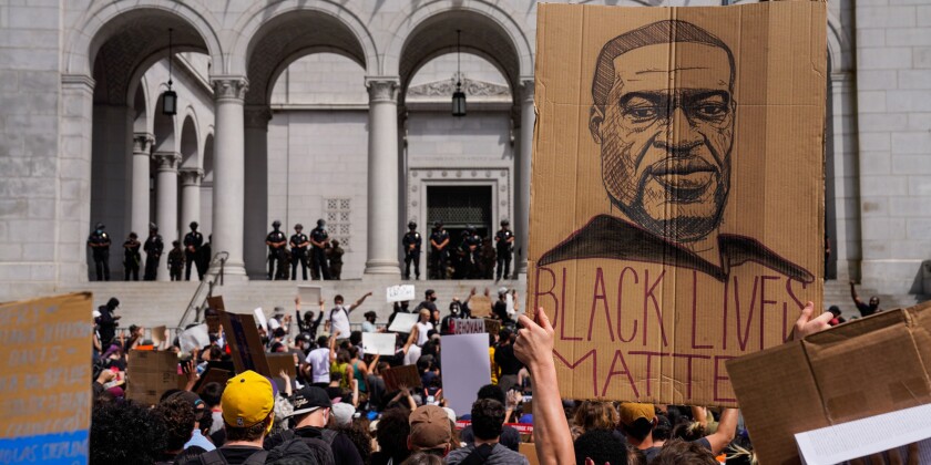 A sign with George Floyd's image and the words "Black Lives Matter" is raised amid a crowd of protesters at L.A. City Hall