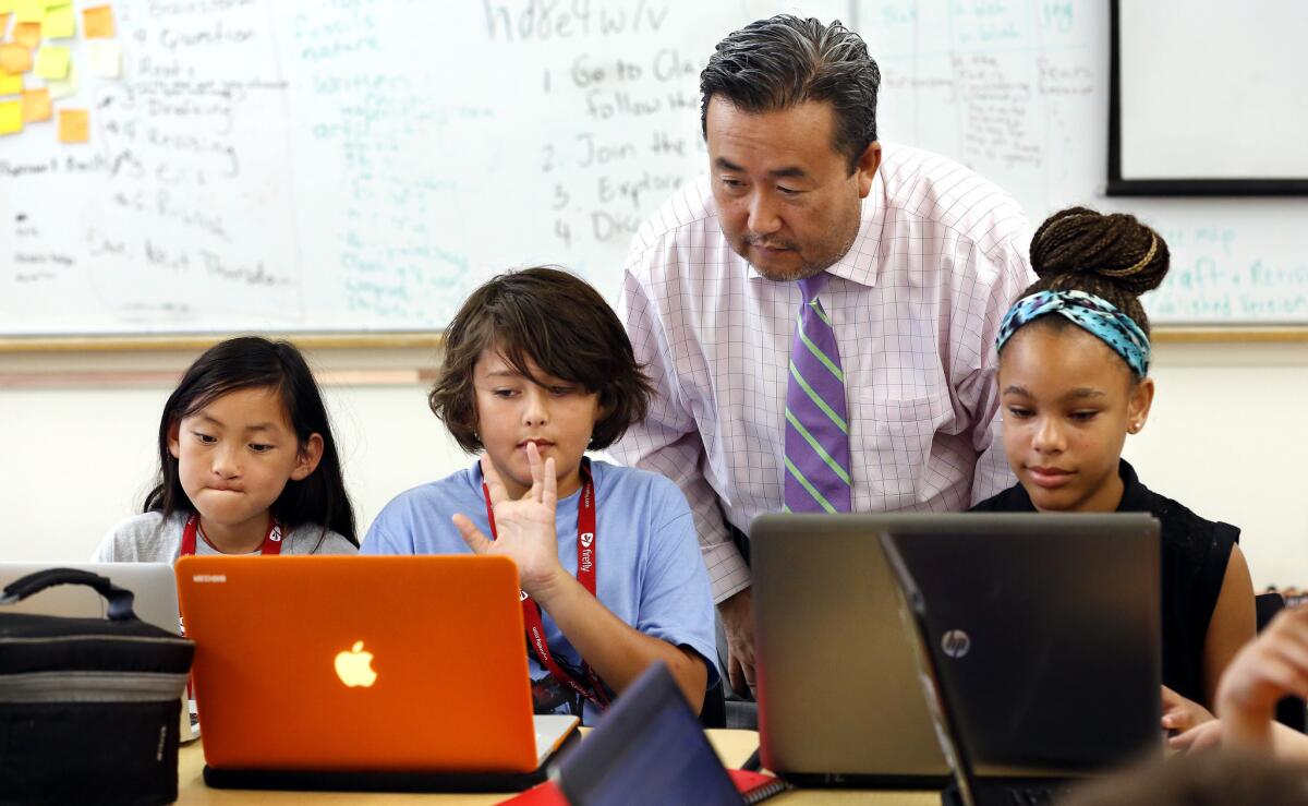 Principal Roy Park with sixth-graders graders, from left, Rebecca Halbert, 11, Bodhi Seidman, 10, and Kennedy Williams, 11, create a video game in a class where students learn to work in startups and manage their time.