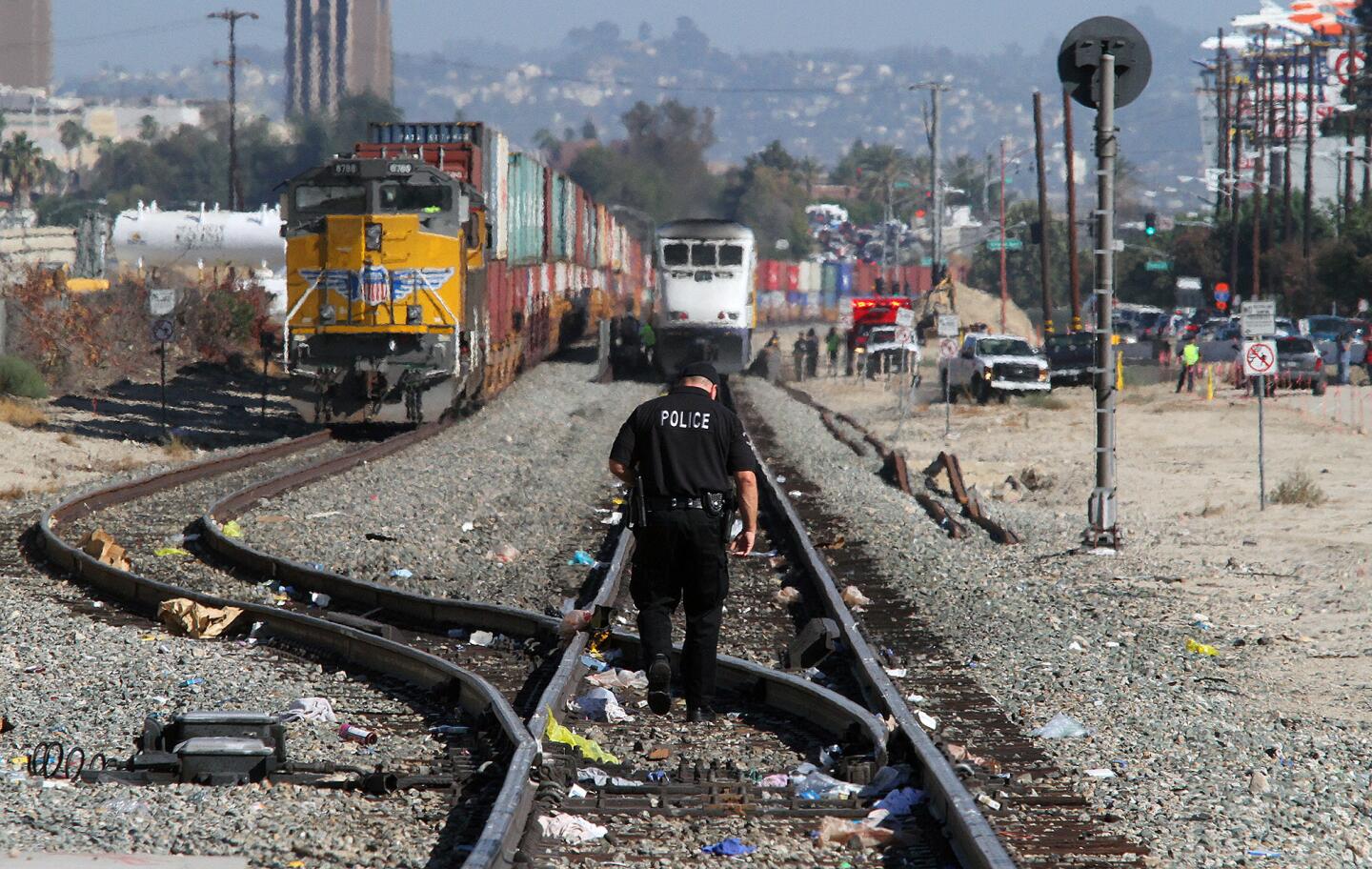 A Burbank police officer, with the involved Metrolink train in the distance, walks along the tracks in search of evidence of a collision between a motorist and a Metrolink train at the intersection of San Fernando and Buena Vista in Burbank on Monday, September 2, 2014. The southbound train struck a motorist allegedly driving around the downed crossing arms on Buena Vista totalling the vehicle and sending the driver to the hospital with critical injuries.
