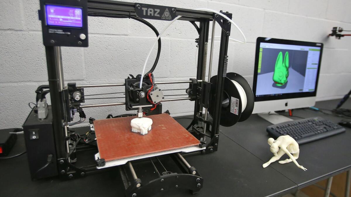 A 3-D printer creates a plastic model, left, from the image on a computer, right, of Laguna College of Art + Design student Alexis Resenbeck's design of a serval, an African wild cat.