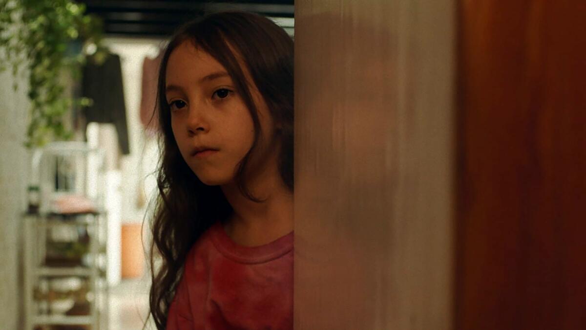 A young girl stares into a room.