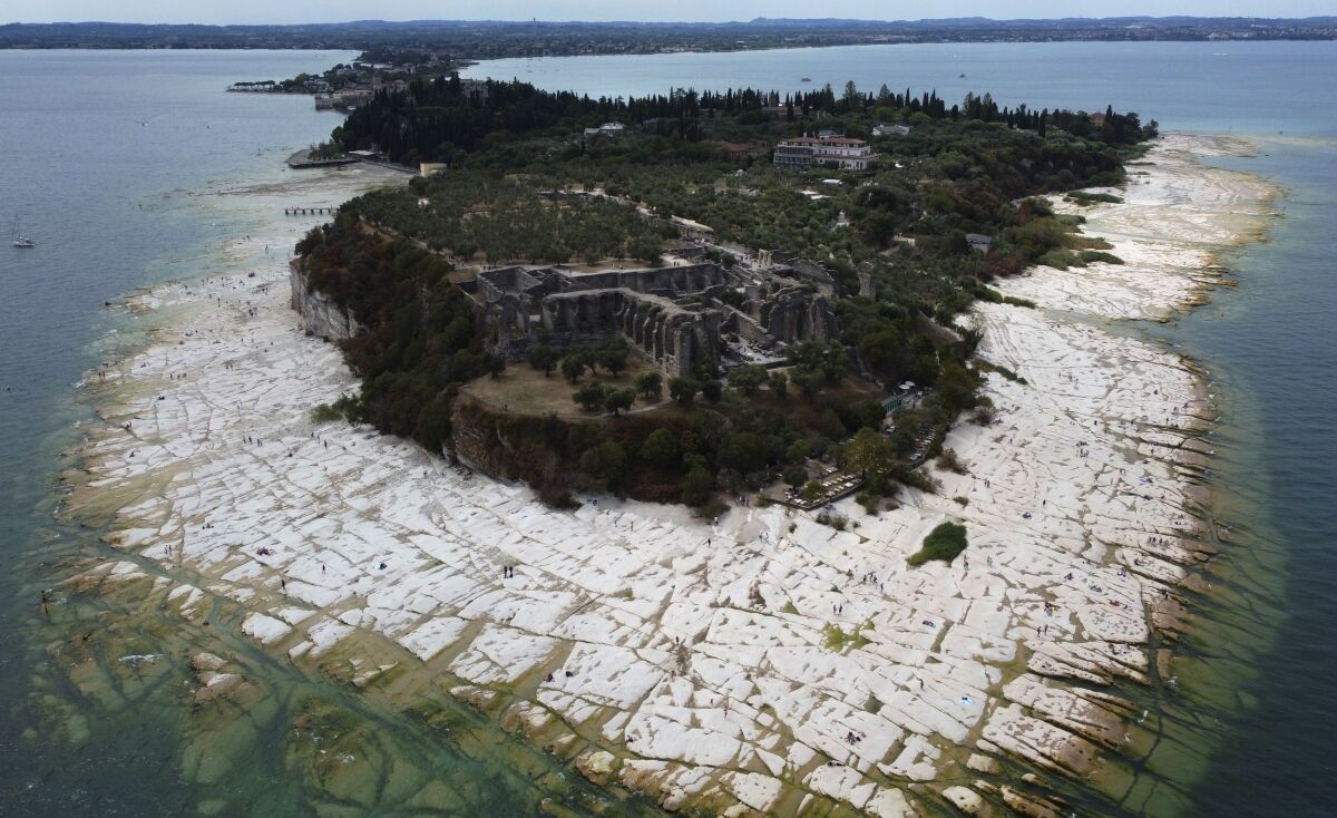 Vista de la península de Sirmione, sobre el lago Garda, Italia, 12 de agosto de 2022. El nivel del agua en el lago Garda ha bajado críticamente debido a una aguda sequía, y aparecen rocas en torno de la península de Sirmione. (AP Foto/Antonio Calanni)
