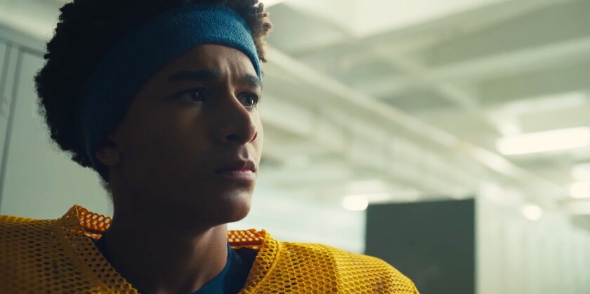 A teenage boy in a blue headband and yellow football jersey