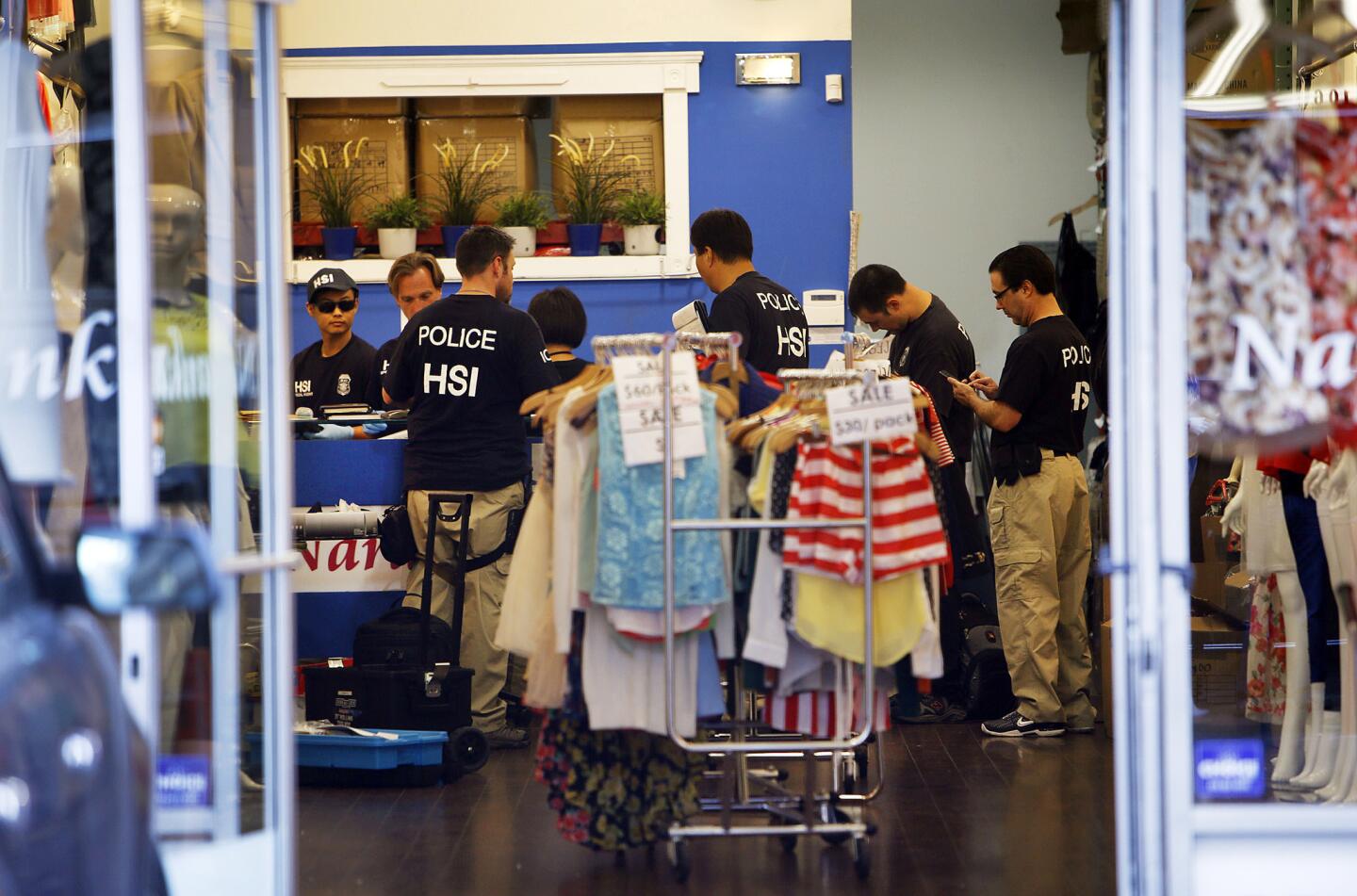 Federal agents gather evidence from a business as they launched a series of raids in the downtown Los Angeles fashion district.