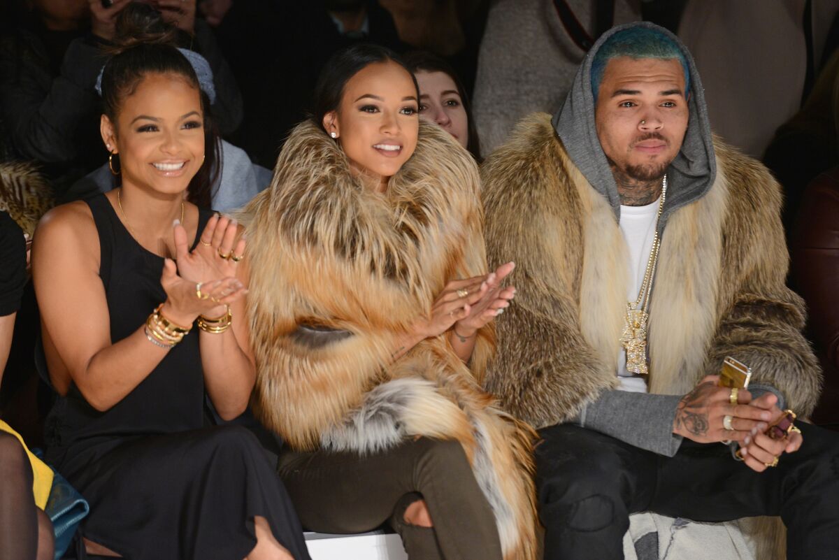 Christina Milian, left, Karrueche Tran and Chris Brown sat front-row at the Michael Costello fashion show in New York City a month ago. About two weeks later, she dumped him on Twitter after learning he had a 9-month-old daughter.