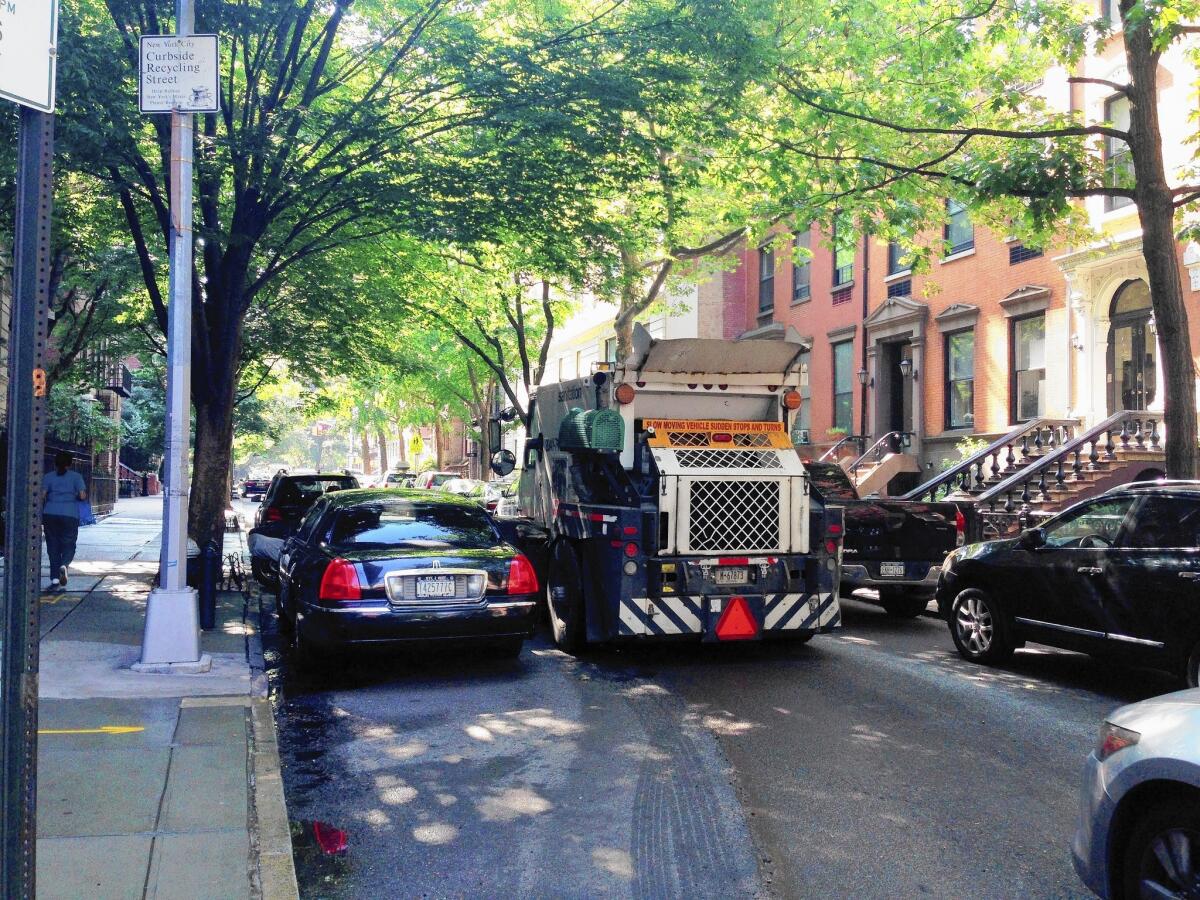 A street sweeper maneuvers around illegally parked vehicles in New York.