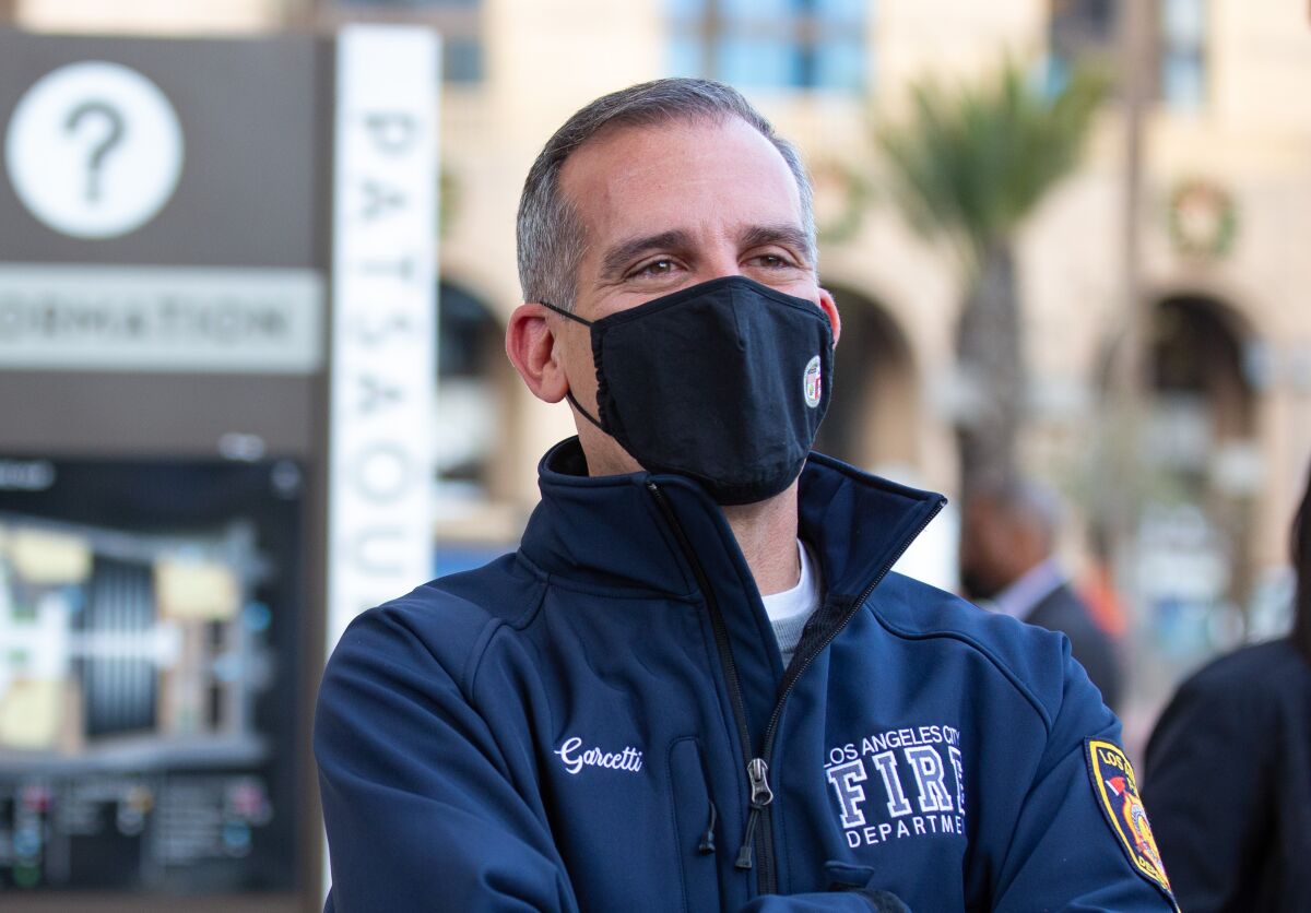 Mayor Eric Garcetti standing outside wearing a face mask.