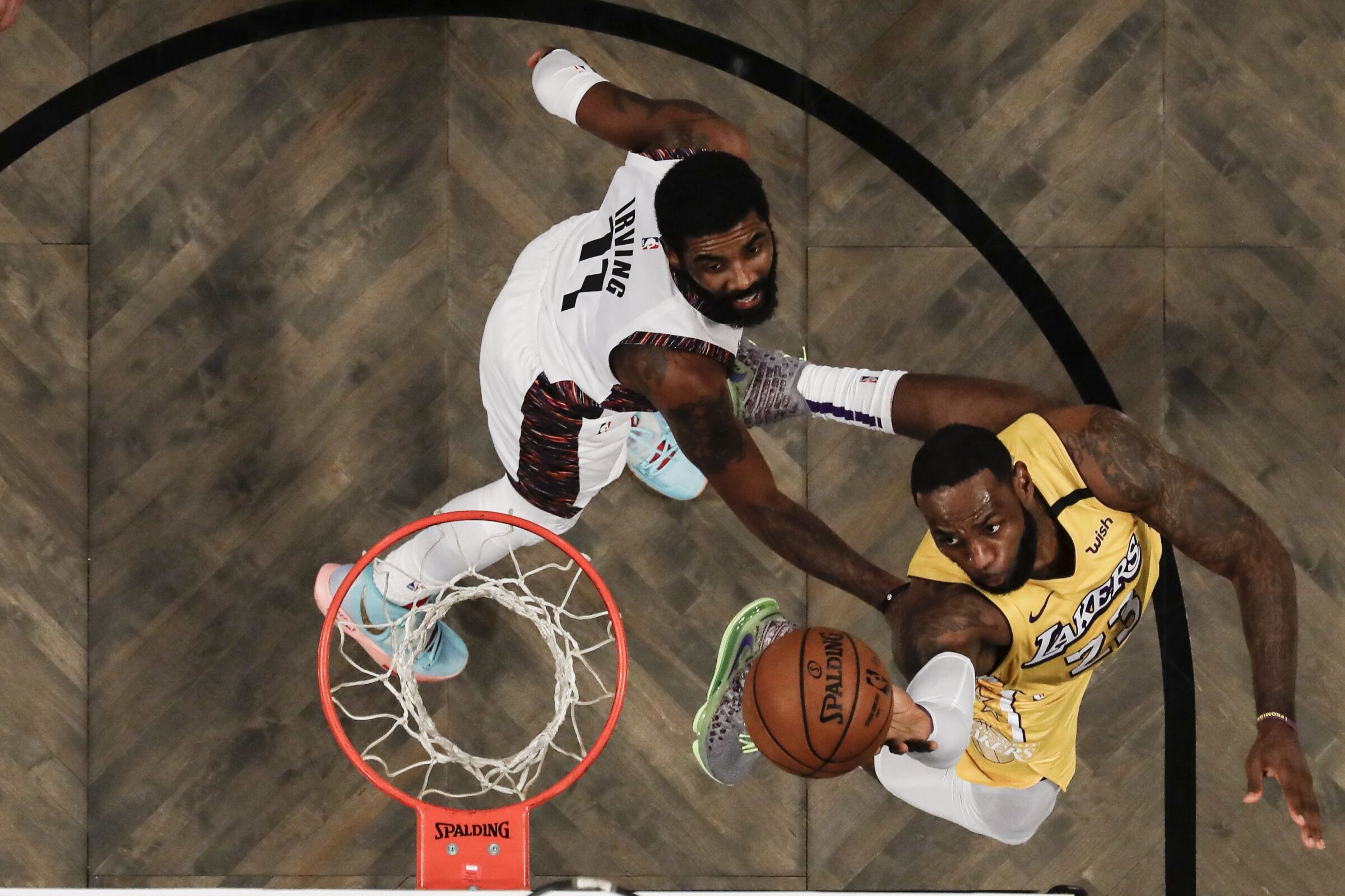 An above-the-basket view of Lakers forward LeBron James attempting a layup against Nets guard Kyrie Irving.