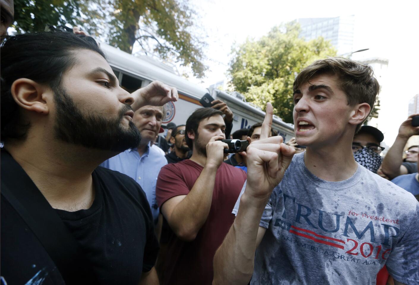 A man wearing a T-shirt bearing the name of President Donald Trump, right, argues with a counter-protester after being hit by a plastic bottle of water near a "free speech" rally staged by conservative activists.