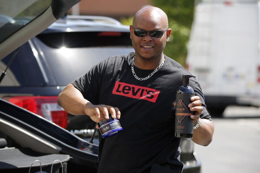 Ray Williams, 42 of Lakewood, poses for a photo as he shows the face products he ordered for himself from Nordstrom, as the South Coast Plaza starts the SCP 2 GO, a contact-free curbside pickup program, in Costa Mesa on Friday, May 15, 2020.