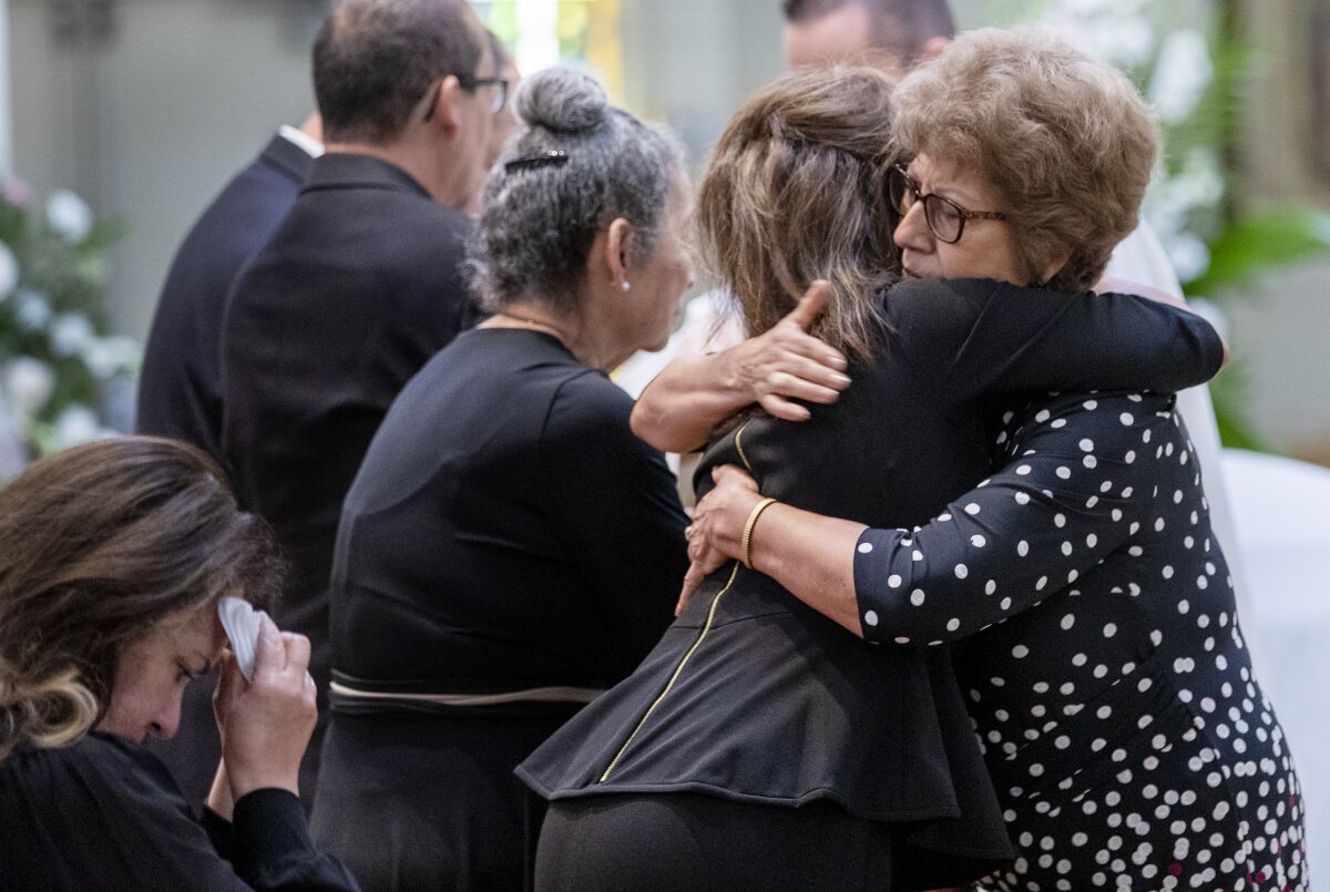 People hug at the funeral of Ernest Z. Robles