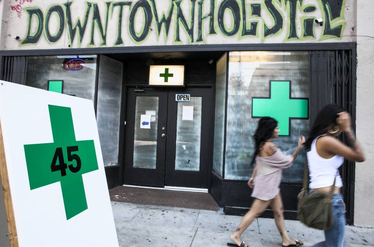 Pedestrians walk past a medical marijuana dispensary in Echo Park on Tuesday, when the Los Angeles City Council voted to ban pot shops.