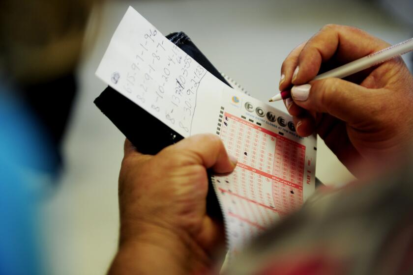 A customer fills out her Powerball ticket inside Bluebird Liquor in 2013 in Hawthorne. The store is expected to see a rush of business with Saturday's jackpot at an unprecedented high.