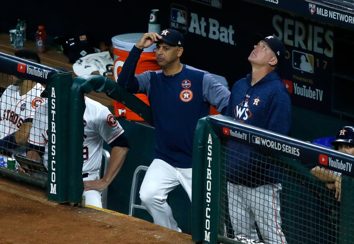 Bench coach Alex Cora, left, and manager A.J. Hinch of the Houston Astros look on from the dugout during Game 5 of the 2017 World Series against the Dodgers.