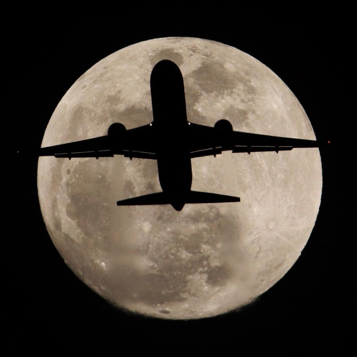 An airplane headed to Los Angeles International Airport crosses in front of the full moon over Whittier, California, Tuesday evening.