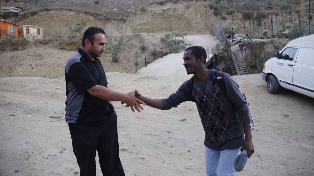 The Rev. Gustavo Banda, pastor at Templo Embajadores de Jesus, left, greets a Haitian migrant. The church offers housing to more than 60 Haitians.
