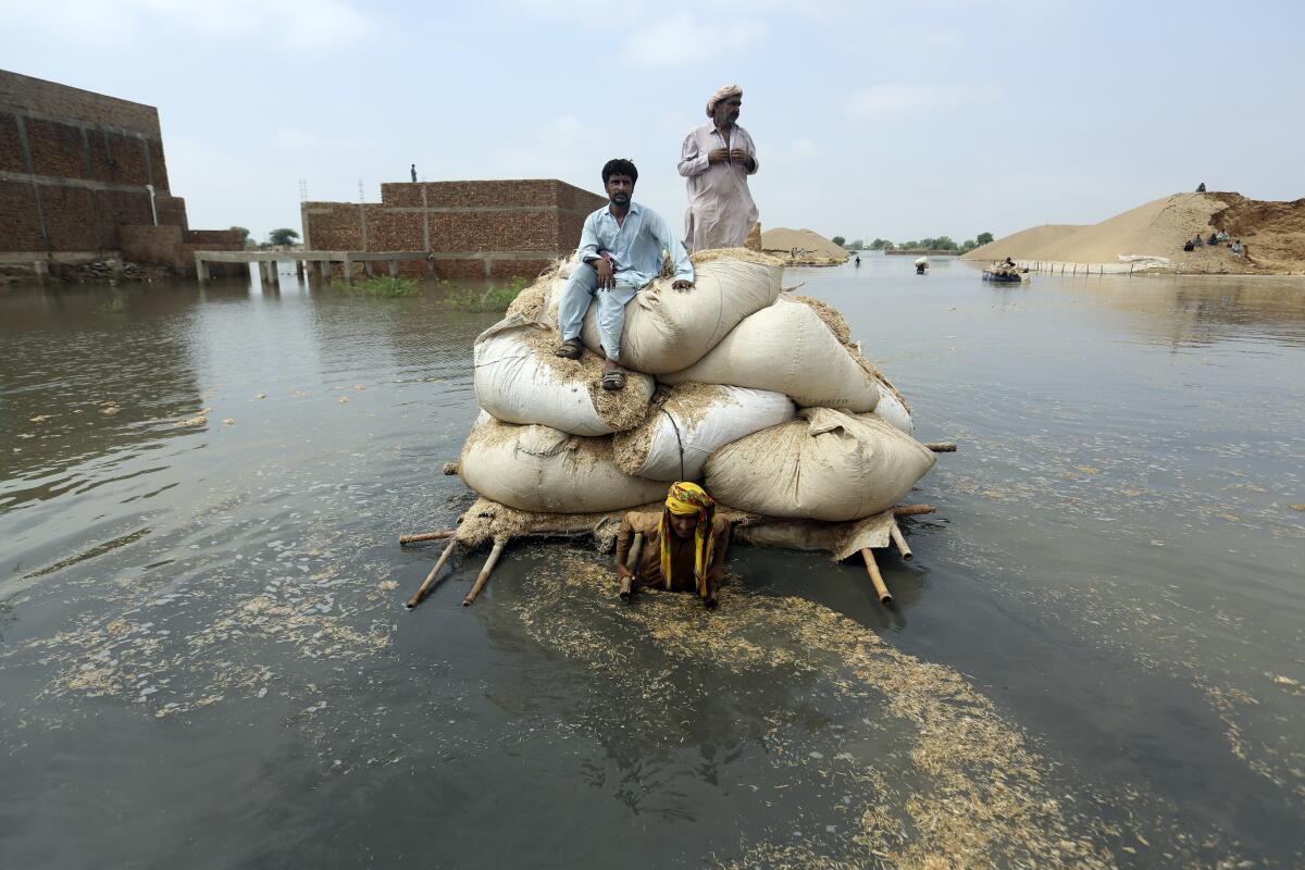 Victims of the unprecedented flooding from monsoon rains use makeshift barge to carry hay for cattle, in Jaffarabad, a district of Pakistan's southwestern Baluchistan province, Monday, Sept. 5, 2022. The U.N. refugee agency rushed in more desperately needed aid Monday to flood-stricken Pakistan as the nation's prime minister traveled to the south where rising waters of Lake Manchar pose a new threat. (AP Photo/Fareed Khan)