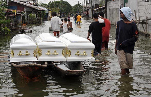 A boatman transports three empty wooden coffins above floodwaters on the edge of the Laguna Lake east of Manila on Thursday. Floods killed 298 people and submerged 80% of the capital. At least 400,000 squatters blocking key drainage channels of a giant lake on the edge of the Philippine capital need to be uprooted to fix Manila's flooding crisis, a government official said.