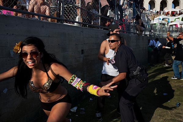 An audience member runs from a Los Angeles police officer after several people rushed a fence separating fans in seats from fans on the lawn during the 14th annual Electric Daisy Carnival at the Coliseum on Saturday. The two-day event drew more than 185,000 people. See full story