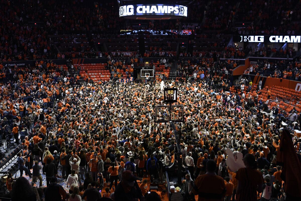 Illinois fans storm the court at the conclusion of an NCAA college basketball game against Iowa, Sunday, March 6, 2022, in Champaign, Ill. (AP Photo/Michael Allio)