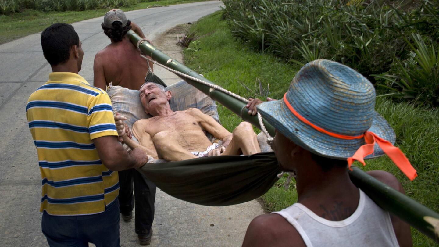 An elderly man, who was in the hospital before Hurricane Matthew hit, is carried back to his home in a hammock, in Baracoa, Cuba.